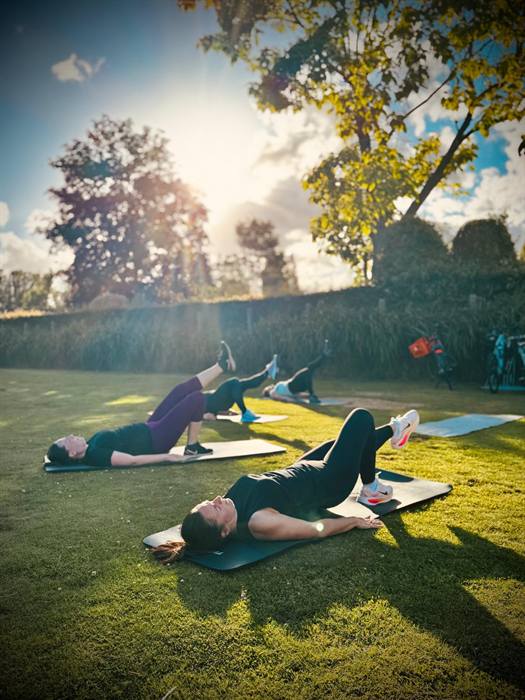 Vrouwen op matjes in het gras tijdens een training in de avondzon