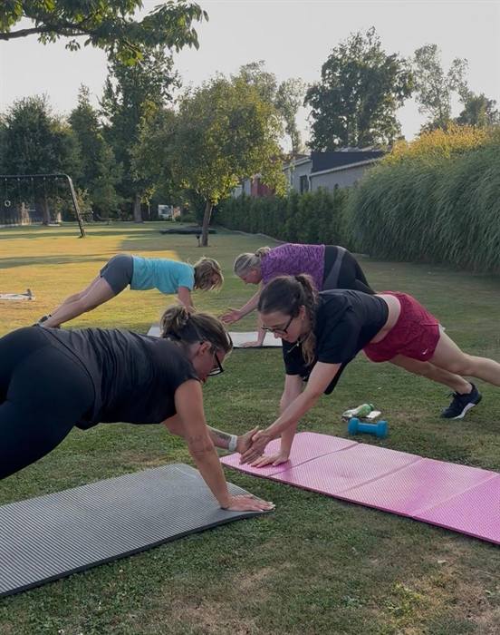 Vrouwen die elkaar een high five geven in plankhouding op het gras