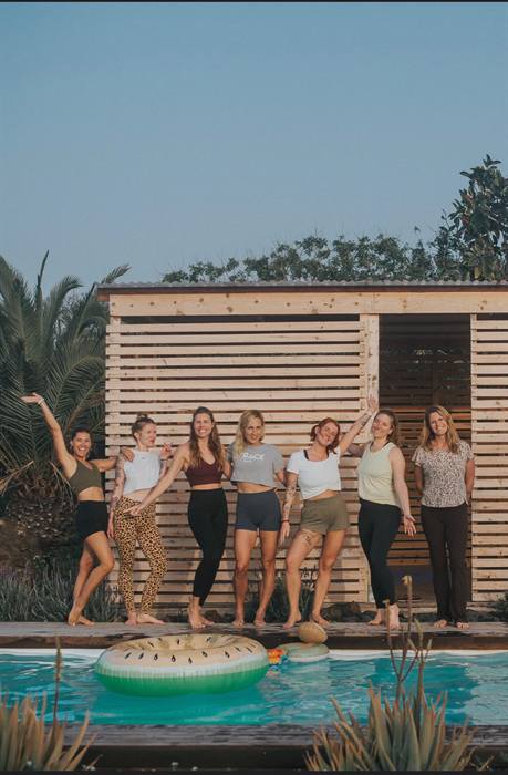 Groep vrouwen lachend naast het zwembad tijdens een retreat